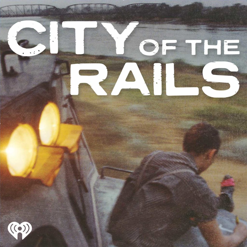 Motion shot of a man sitting on the front of a locomotive with the text City of the Rails on top